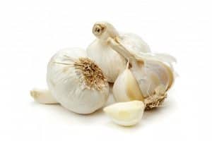 Bulbi d'aglio interi e uno spicchio sbucciato su sfondo bianco